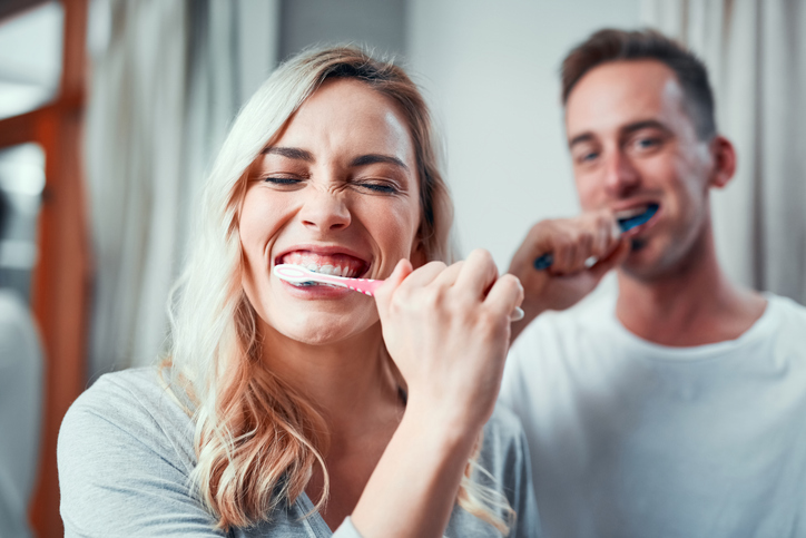 female and male couple brushing their teeth