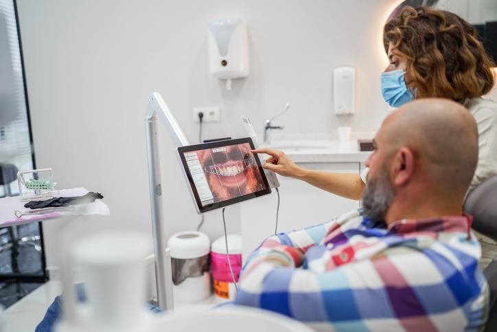 male dental implant patient looking at his new teeth on a monitor